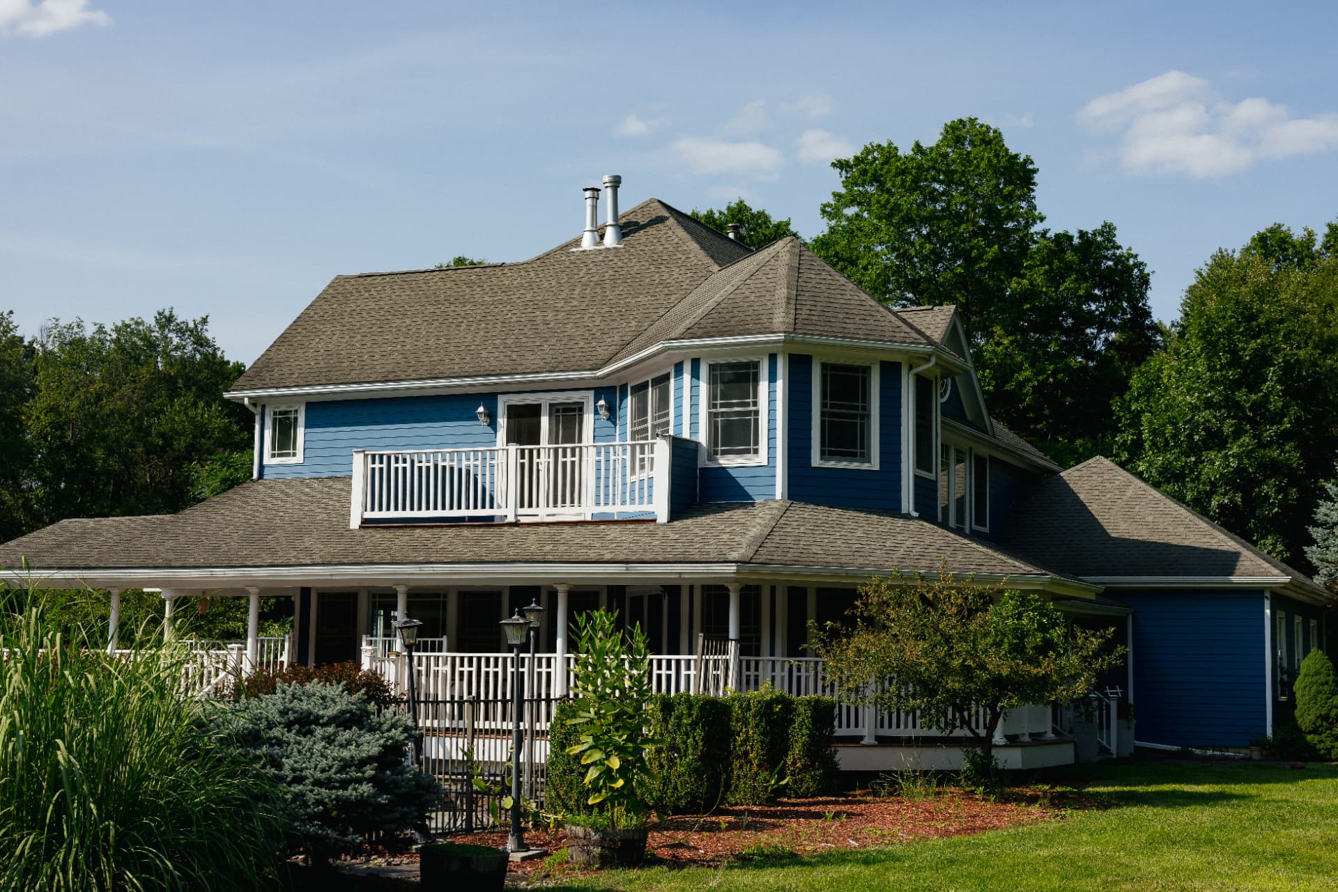 Front of the blue estate house with its wraparound porch