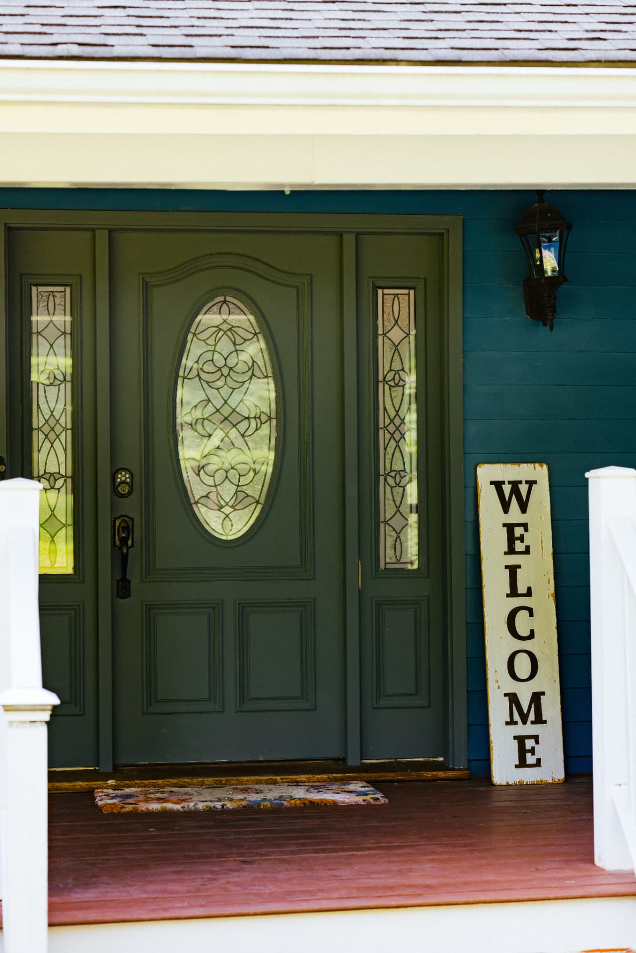 Green front door with a welcome sign on the porch
