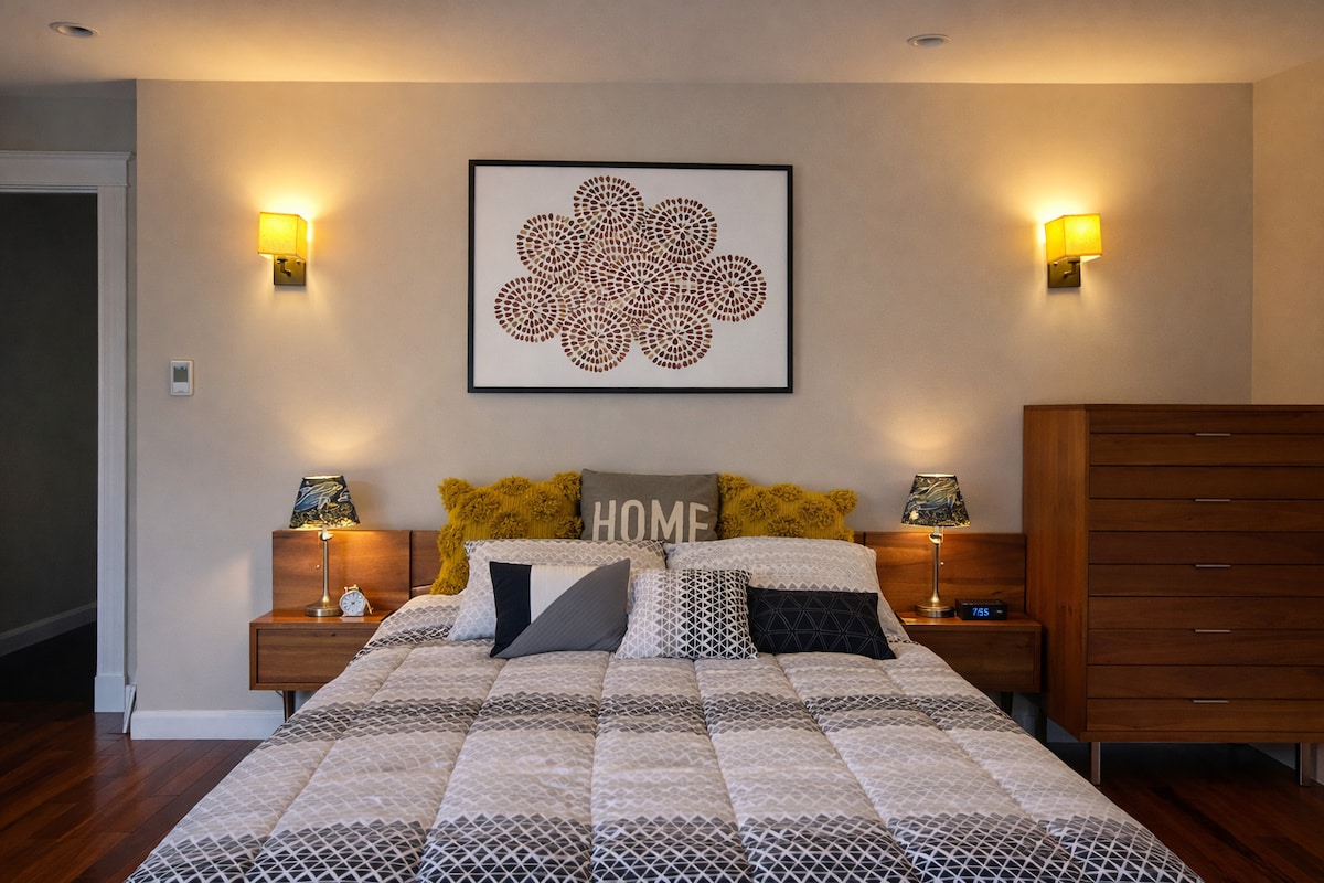 The Amber Suite at Thee Wild Lux — warm amber wall sconces, king mid-century bed, original art above headboard